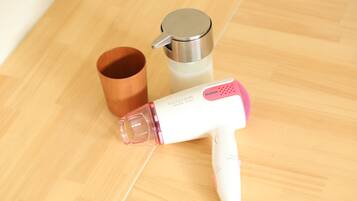 A hair dryer, a thermos, and a wooden cup on a wooden floor.