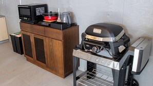 A kitchenette with a microwave, a red pot, a kettle, and a grill. - Glamping Resort ITU (Nasu)
