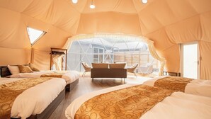 A spacious tented accommodation with two beds, a sofa, and a dining area. - Glamping Resort ITU (Nasu)