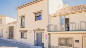 Un edificio de dos pisos con un balcón, una puerta y una ventana.
