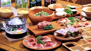 A variety of food items and beverages on a wooden table, including bowls of salad, plates of meat, and bottles of beer. - Resonate Glamping Hoshi no Oka (Taketa)