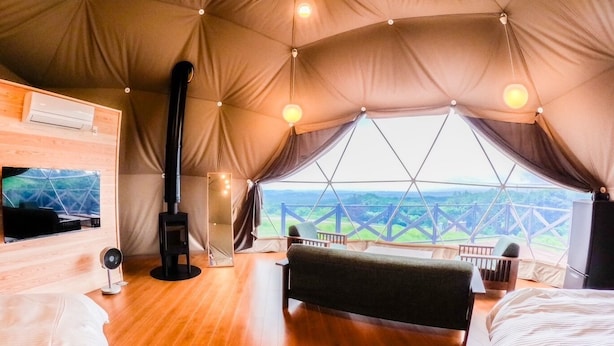 A tent with a wooden floor, a bed, a mirror, and a TV. - Resonate Glamping Hoshi no Oka (Taketa)
