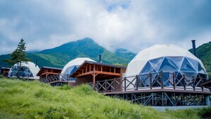 Geodesic dome cabins with wooden decks and a mountain backdrop. - Resonate Glamping Hoshi no Oka (Taketa)