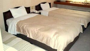 Una camera d'albergo con due letti singoli, un comodino e una finestra con tende.