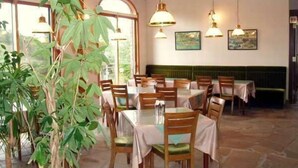 Un ristorante con tavoli e sedie, ampie finestre e lampadari.
