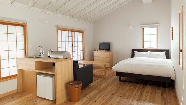 Een compacte slaapkamer met een bed, een klein bureau, een stoel en een televisie.
