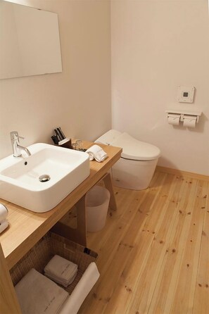 Een moderne badkamer met een wit wastafel, houten opbergmeubel en een toilet.