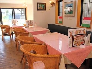 Ein Restaurant mit Korbstühlen und Tischen, die mit rosa Tischdecken bedeckt sind.