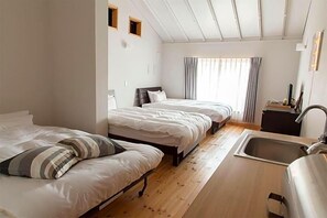 Une chambre d’hôtel avec deux lits, un plancher en bois, un lavabo et une fenêtre avec des rideaux.