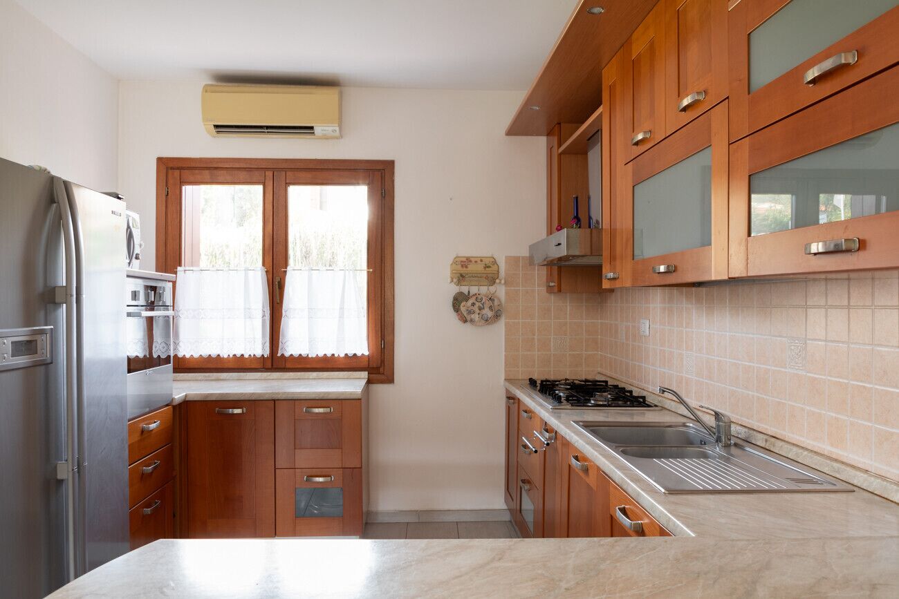 Una cocina compacta con armarios de madera, un refrigerador de acero inoxidable, una estufa a gas y un lavamanos.