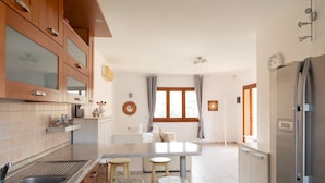 Eine moderne Küche mit Holzausstattung, einer Marmorarbeitsplatte und einer zentralen Kochinsel mit Barhocker.