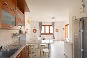 Una cocina moderna con armarios de madera, encimera de mármol y una isla central con taburetes.