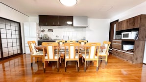 A dining area with a round table and chairs, a kitchen with cabinets and appliances, and a wooden cabinet with a microwave.