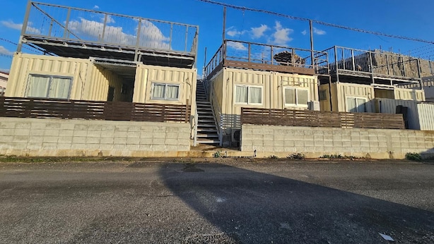 A building with a concrete base, a wooden deck, and a metal railing.
