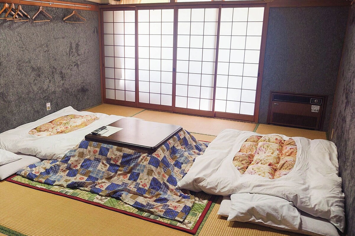 A traditional Japanese-style room with tatami flooring, a low table, and shoji screens.