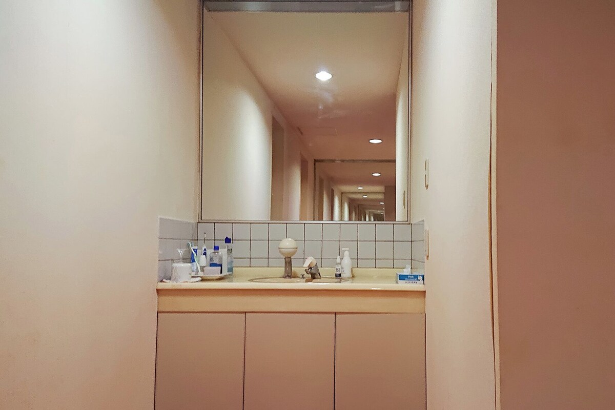 A bathroom with a mirror, sink, and toiletries.