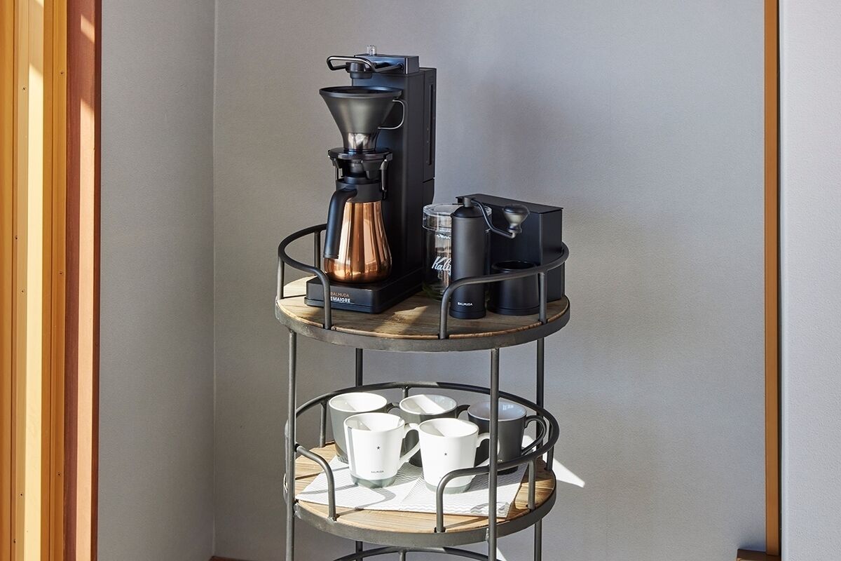Eine dreistufige Metall-Kaffeestation mit Kaffeemühle, Kaffeekanne und Wasserkocher.