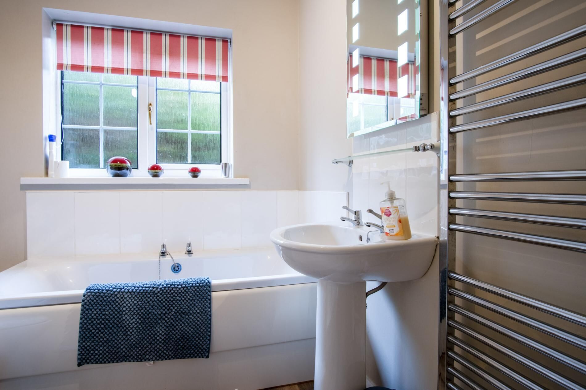 A bathroom with a bathtub, a sink, and a window with a striped blind.