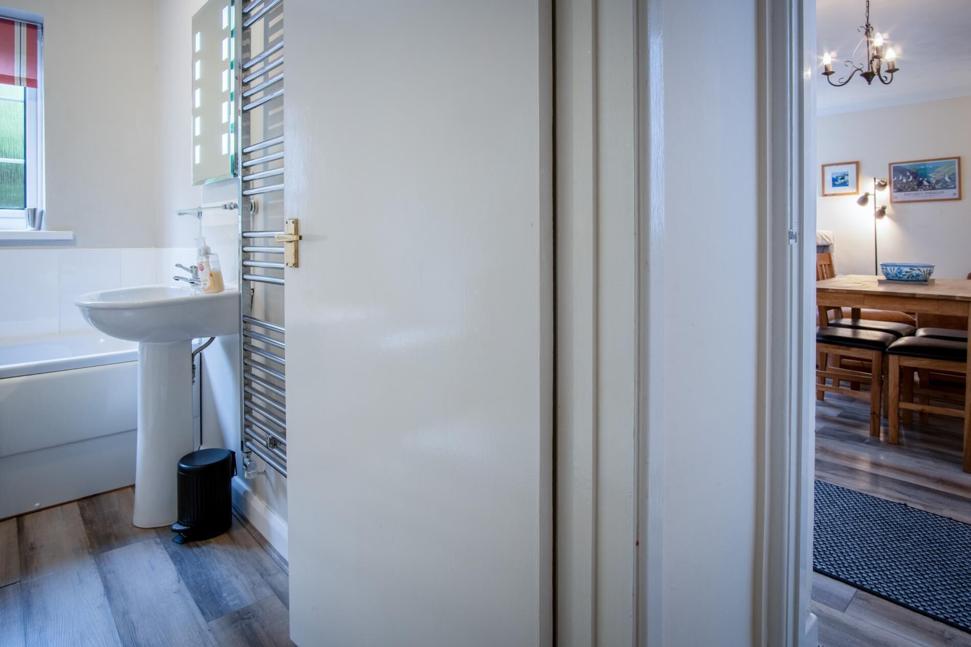 A modern bathroom with a white sink, a bathtub, and a towel rack.