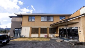 A modern building with a flat roof, large windows, and a covered entrance area. - Kappo Ryokan Magohachi (Nakatsugawa)