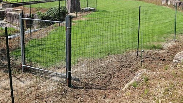 A fenced outdoor area with a grassy field, a large rock, and a tree. - Kappo Ryokan Magohachi (Nakatsugawa)