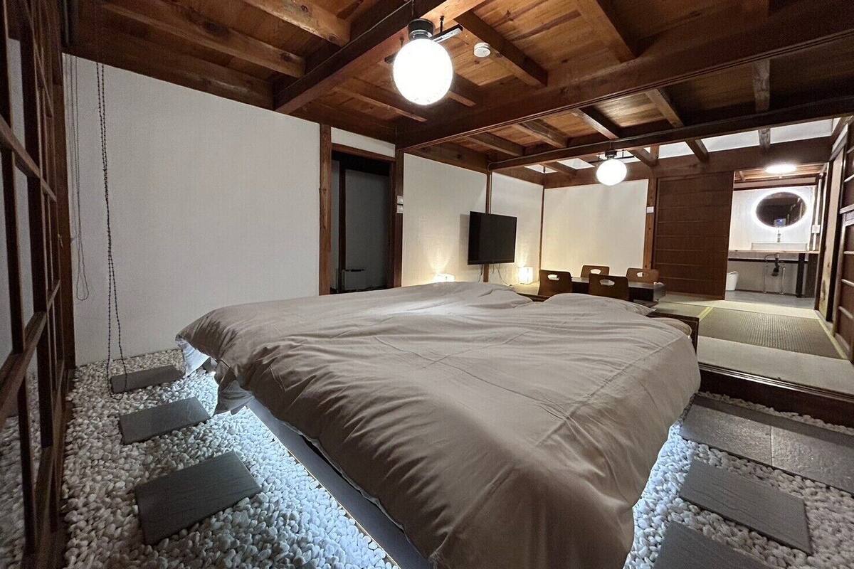 A bedroom with a large bed, wooden ceiling beams, a television, and a mirror.