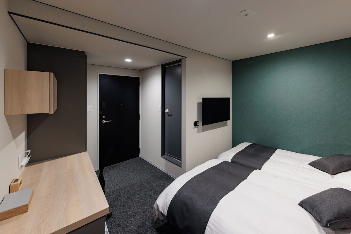 Una habitación de hotel moderna con una cama, un escritorio, un televisor y una puerta que da a otra habitación.