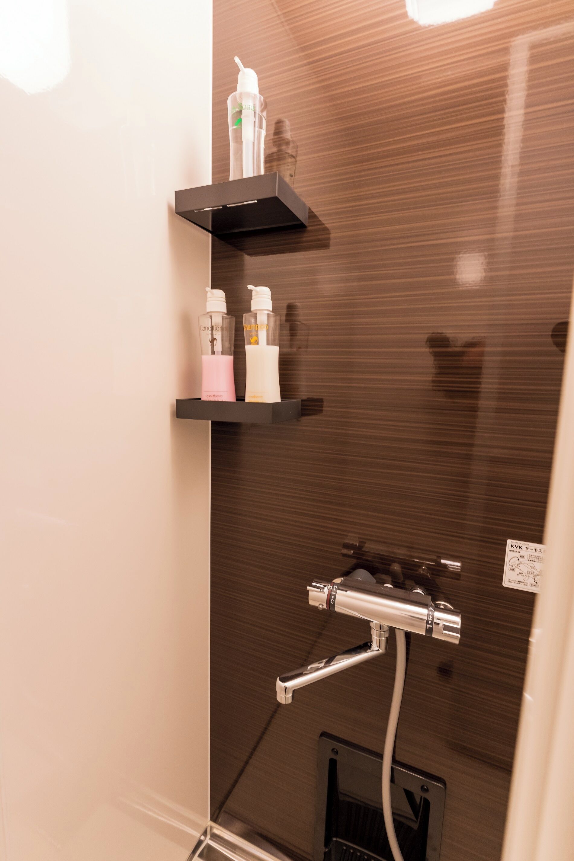 A bathroom with a shower, a shelf with toiletries, and a mirror.