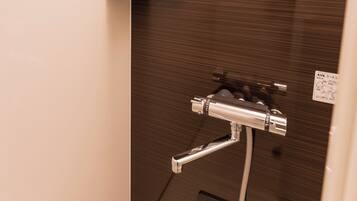 A bathroom with a shower, a shelf with toiletries, and a mirror.