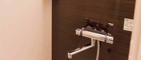 A bathroom with a shower, a shelf with toiletries, and a mirror.