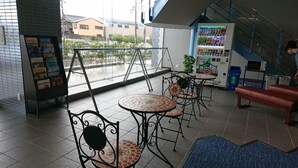 Un café con mesas al aire libre, una máquina expendedora y una escalera que sube a un nivel superior.