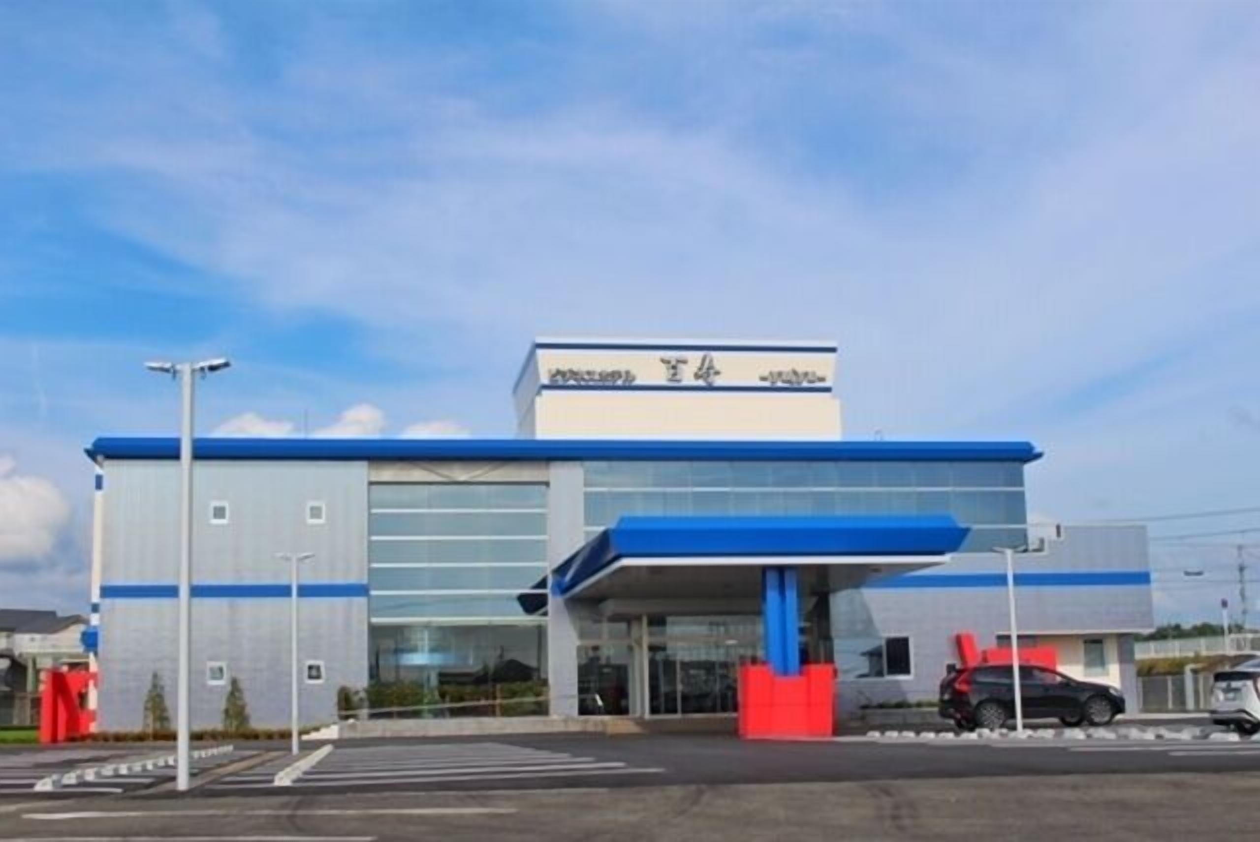 A modern building with a blue and white color scheme, large glass windows, and a prominent entrance with a blue canopy.