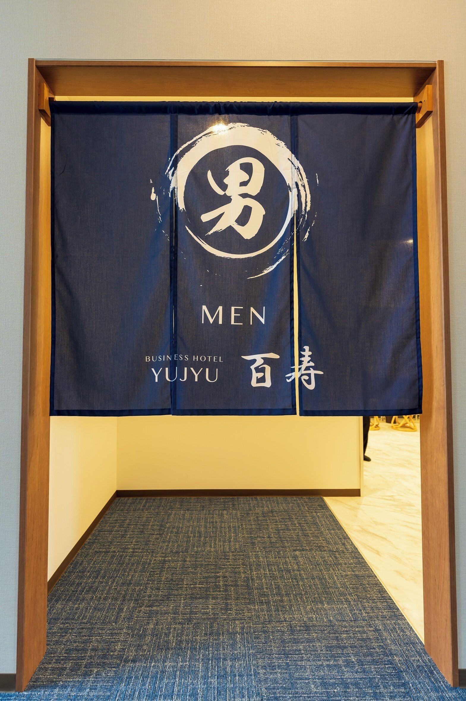 A hotel room with a blue carpet, a wooden frame, and a wall with a large banner featuring the text "MEN" and "YUJYU".