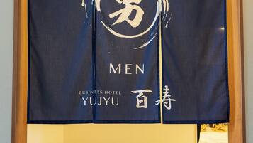 A hotel room with a blue carpet, a wooden frame, and a wall with a large banner featuring the text "MEN" and "YUJYU".