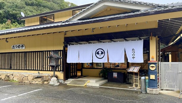 Un edificio japonés tradicional con tejado de tejas y un letrero que dice "たつのや".
