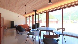 A modern interior with a wooden ceiling, large windows, a central table, and chairs. - Centennial Forest Hotel Shiori (Nishiawakura)