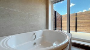 A modern bathroom with a freestanding bathtub, large windows, and a view of a wooden deck. - Centennial Forest Hotel Shiori (Nishiawakura)