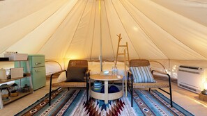 A tent interior with a round table, two chairs, a small bookshelf, a kitchenette, and a sleeping area with a ladder. - Cocohare (Unzen)