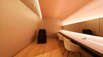 A modern, minimalist room with a long, narrow desk, two chairs, and a black bag on the floor.