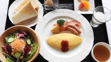 Een dienblad met geroosterde toast, een kom met salade, een omelet met ketchup, een bordje spek, een klein schaaltje bessen, een glas melk en een kop thee.