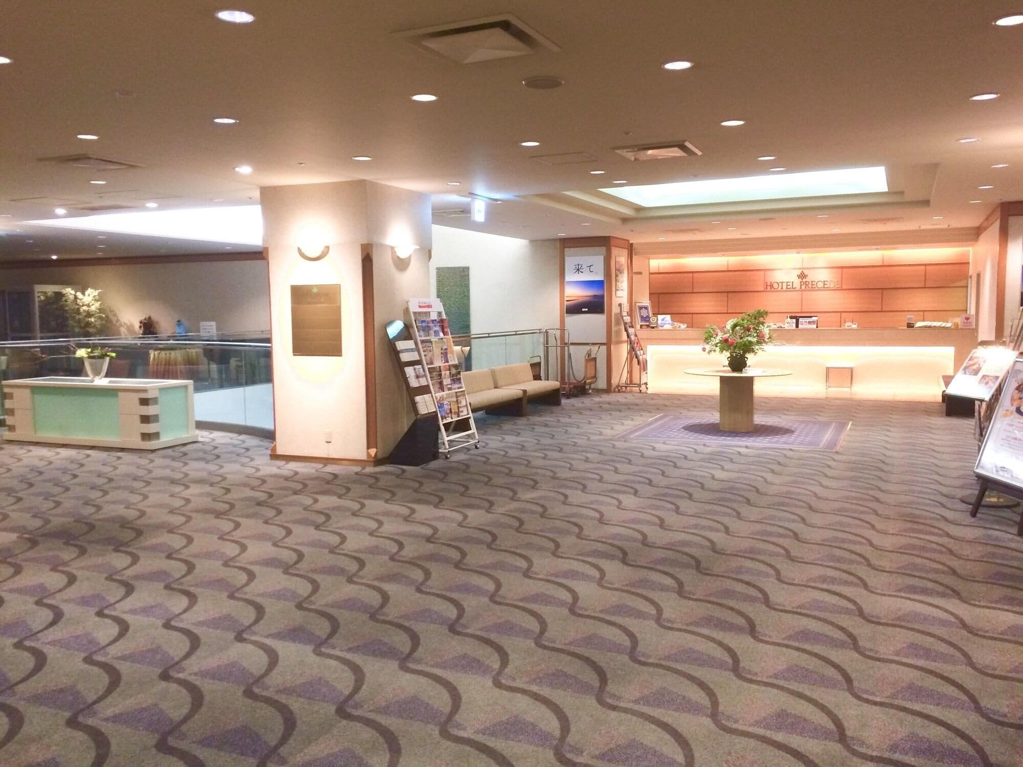 A hotel lobby with a reception desk, seating area, and a large window.