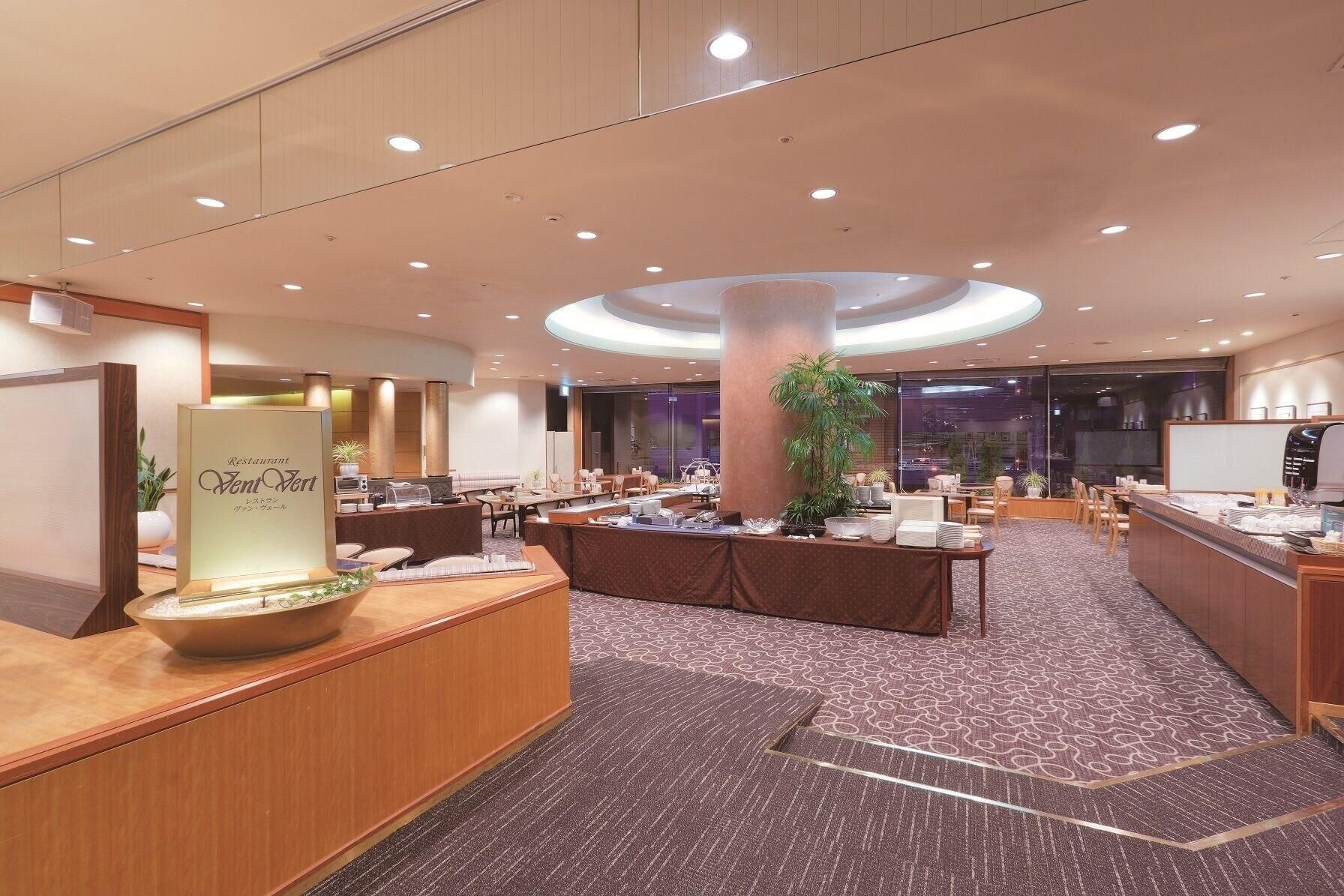 A hotel lobby with a reception desk, seating area, and a large plant.