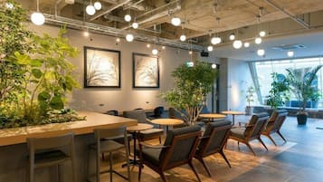 A modern indoor space with tables and chairs, plants, and framed artwork on the walls.