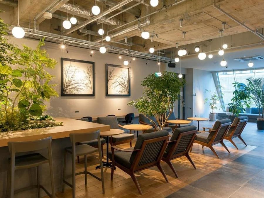 Um espaço interior moderno com mesas, cadeiras, plantas e quadros nas paredes.