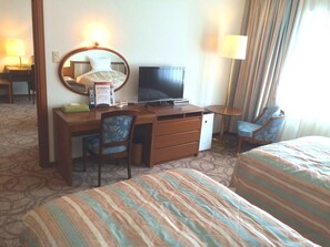 Une chambre d’hôtel comprenant un lit, un bureau avec une télévision, une chaise et une lampe.