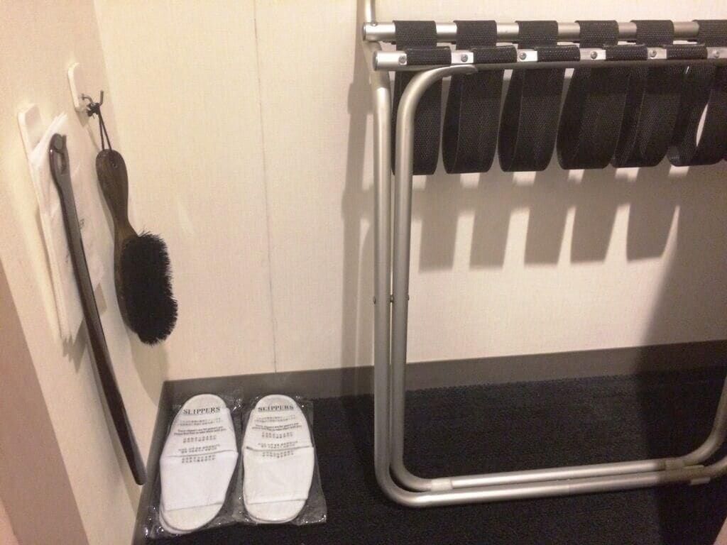 Un baño con un perchero, un cepillo de pelo y un par de pantuflas.