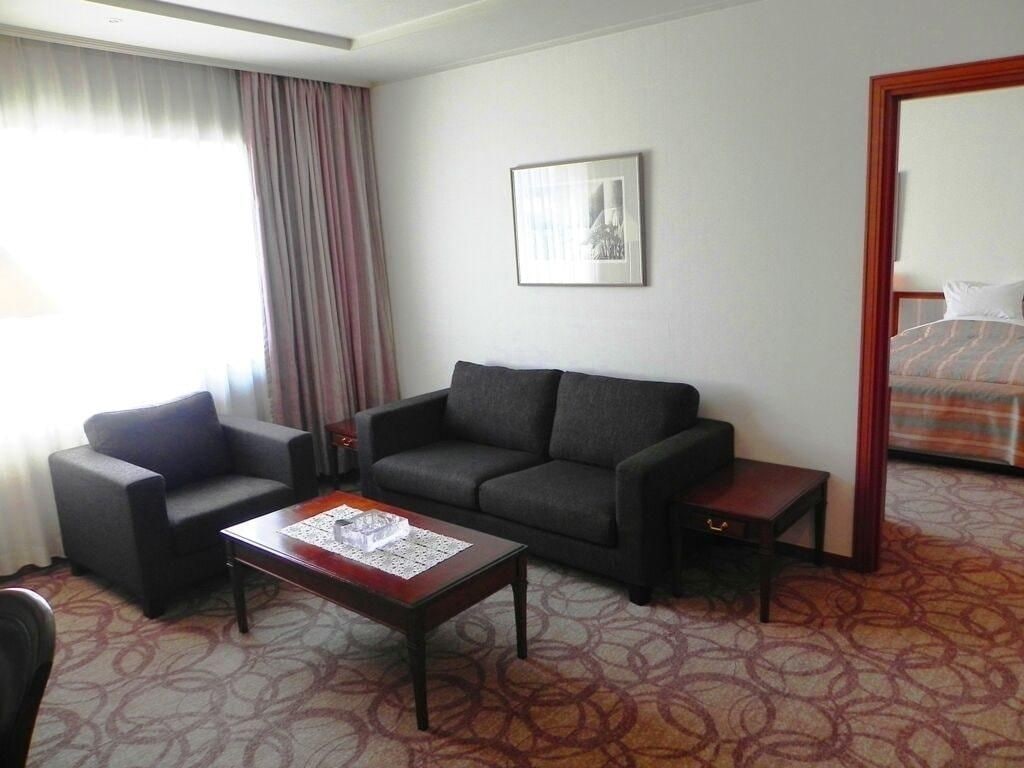 Una habitación de hotel con sofá, mesa de centro y cama.