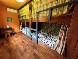 Habitación con literas, suelo de madera, escritorio y silla.