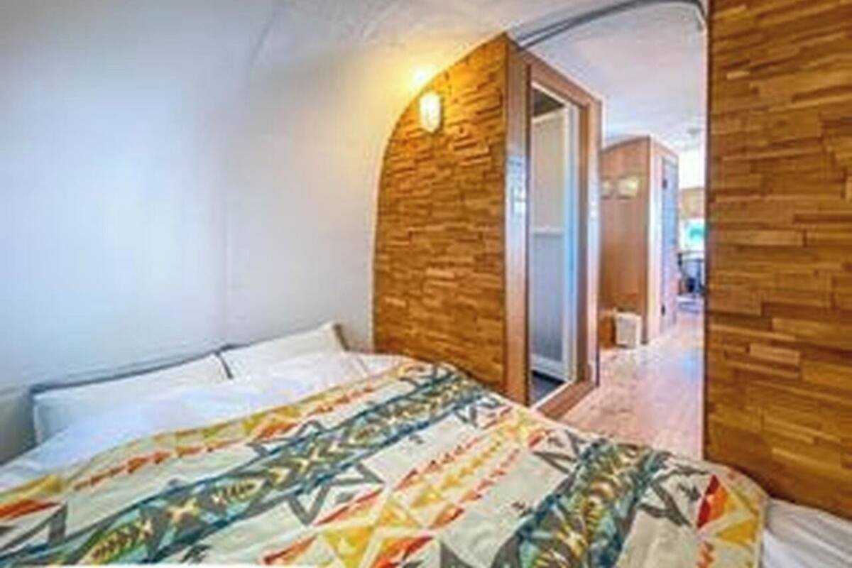 A bedroom with a bed, a wooden accent wall, and a door leading to another room.