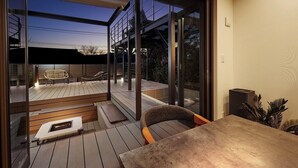 Una terraza moderna al aire libre con piso de madera, una parrilla integrada y zonas de estar.